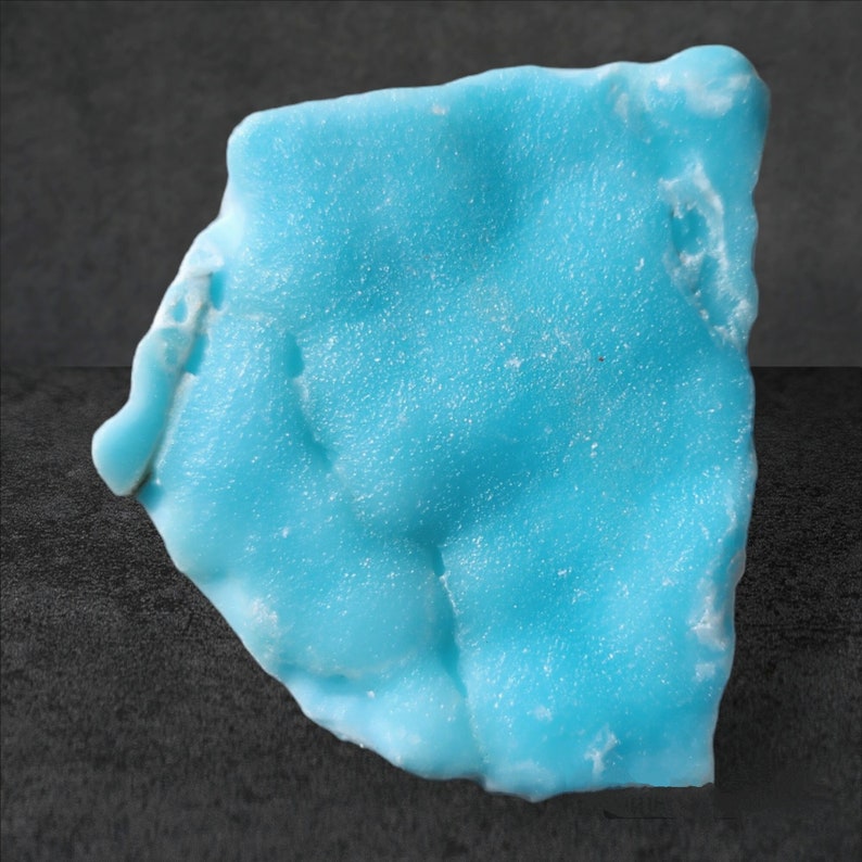 May include: A large, light blue, irregularly shaped piece of turquoise. The turquoise has a rough, textured surface.