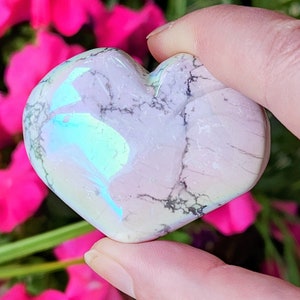 May include: A white heart-shaped crystal with iridescent blue and green hues. The crystal has a marbled pattern and is smooth to the touch.