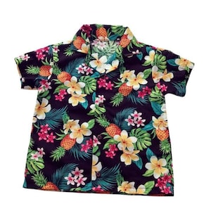 May include: A short-sleeved button-up shirt with a tropical print featuring pineapples, flowers, and leaves on a dark purple background.