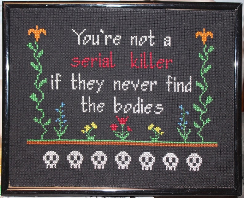 May include: Black framed cross-stitch with the text "You're not a serial killer if they never find the bodies" and five white skull images at the bottom.