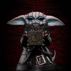 May include: A small, gray, and white figurine of a character with large ears and a black robe. The figurine is holding a small, square, gold-colored box with a symbol on it. The figurine has many small, sharp objects protruding from its head and body.