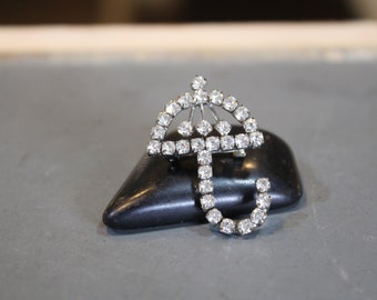 May include: A silver-toned brooch shaped like an umbrella, with clear rhinestones.