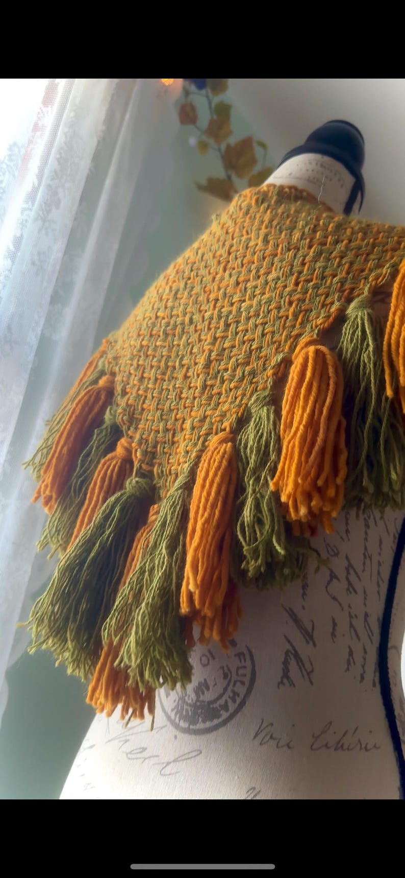 May include: A woven throw blanket with a green and orange pattern and fringe tassels.