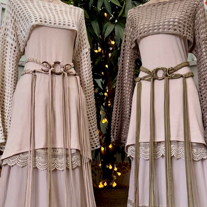 May include: Two long, flowy dresses with crochet tops and layered lace trim. Both dresses feature a brown leather belt with a large metal ring and tassels.