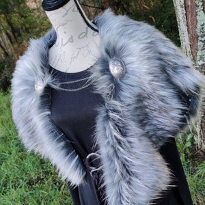 May include: A gray faux fur collar with two silver metal buttons. The collar is on a black dress form.