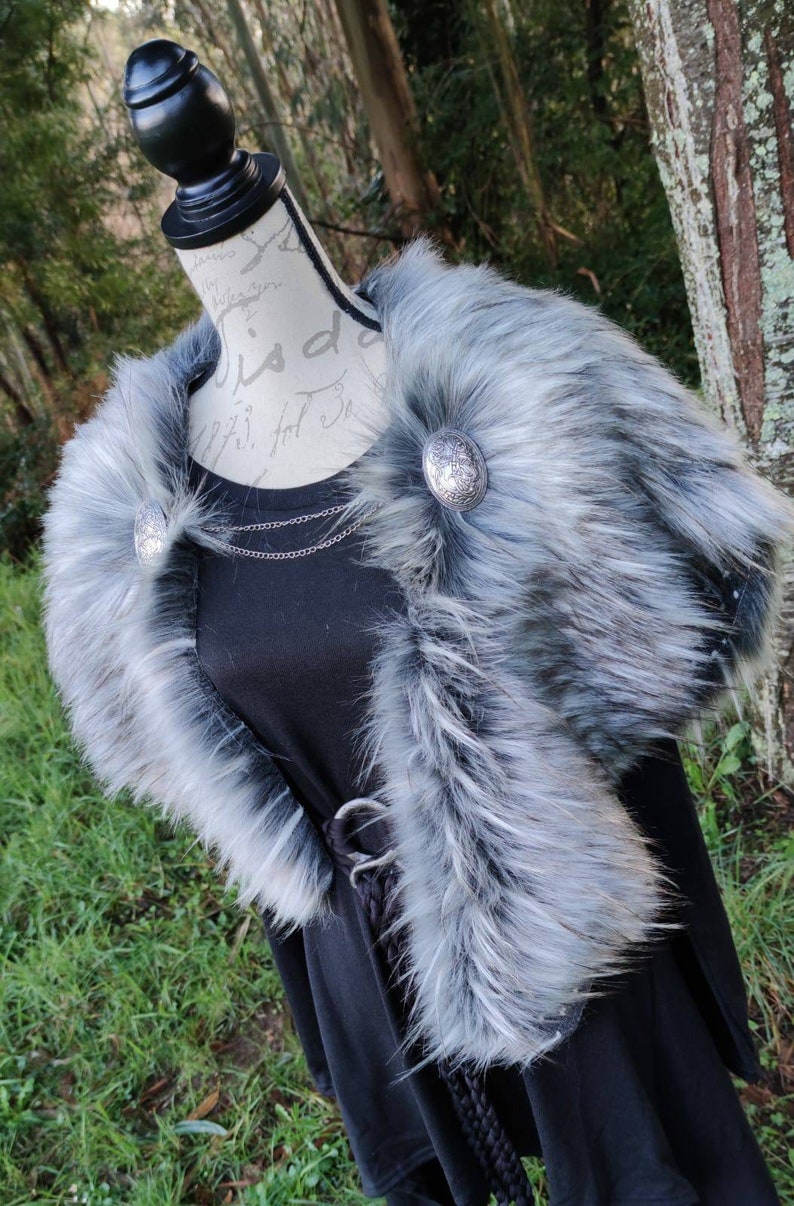 May include: A gray faux fur collar with two silver metal buttons. The collar is on a black dress form.
