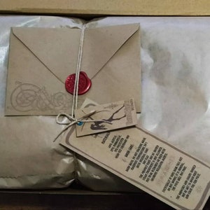 May include: A brown paper package tied with twine and sealed with a red wax stamp. The package includes a small envelope and a tag with the text "MATERIAL 2PINOK MASH CARE STEAR TREATMENT KUND BTWRITESAL THE MORONES AND CARS SHO AS THE FORECL SESAS".