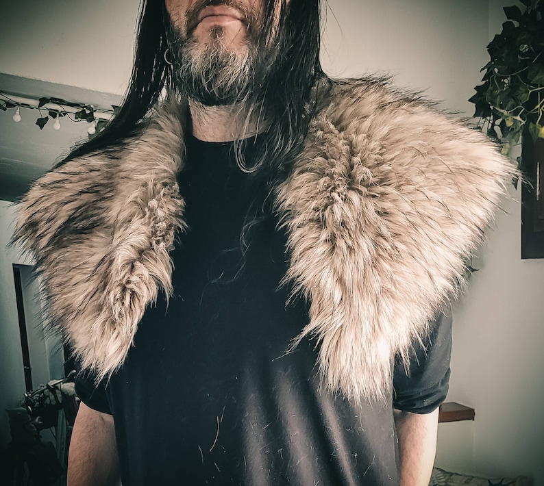 K&ouml;nnte beinhalten: Eine Person tr&auml;gt ein schwarzes Hemd mit einem gro&szlig;en, flauschigen, hellbraunen Pelzkragen.