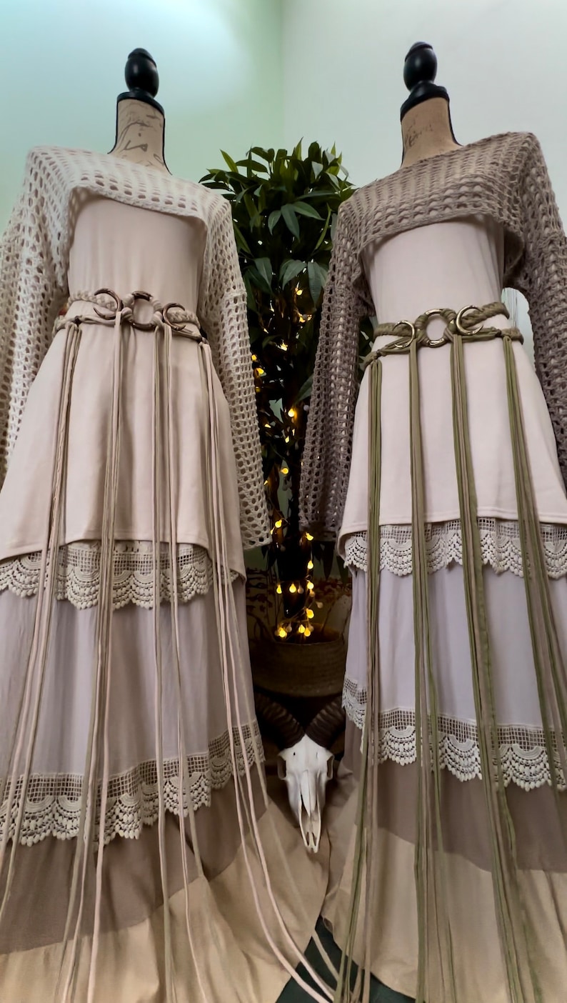 May include: Two long, flowing skirts with lace trim and fringe details. The skirts are layered and have a bohemian style. One skirt is beige and the other is green.