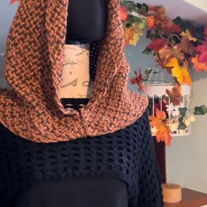 May include: A brown and black crocheted hooded sweater with a black crocheted bottom and long sleeves.