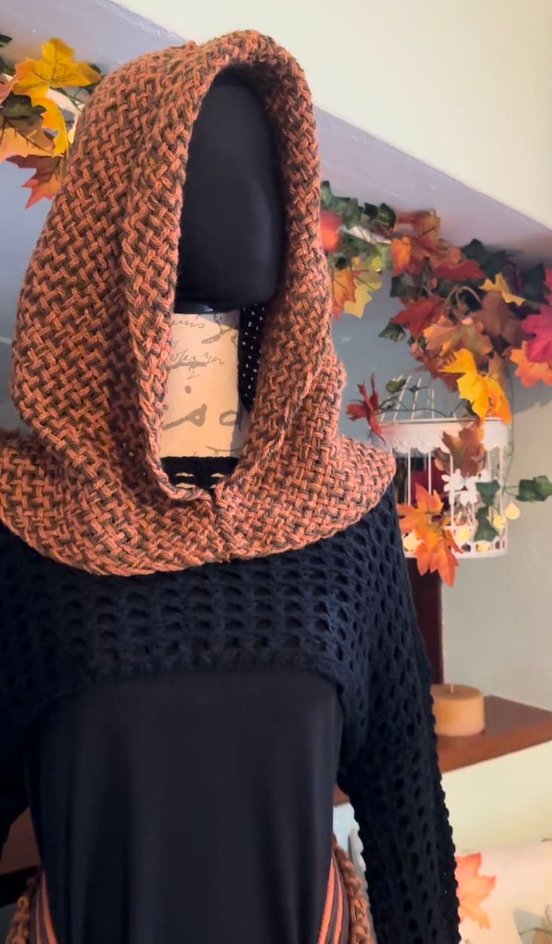 May include: A brown and black crocheted hooded sweater with a black crocheted bottom and long sleeves.