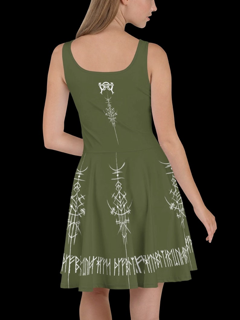 K&ouml;nnte beinhalten: Ein gr&uuml;nes, &auml;rmelloses Kleid mit einem wei&szlig;en Design aus Runen und Symbolen. Das Kleid hat einen figurbetonten Oberteil und einen ausgestellten Rock.