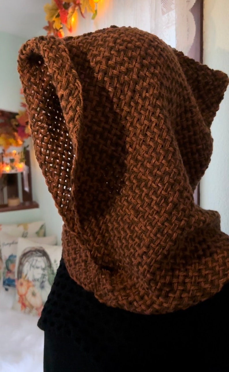 May include: A brown knitted hooded scarf with a textured pattern. The scarf is made of a soft, warm material and is perfect for keeping you warm in the winter.
