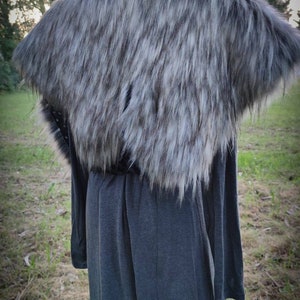 May include: A gray faux fur collar with a long gray dress underneath. The collar is made of soft, fluffy fur and has a slightly textured look. The dress is a simple, long-sleeved design.