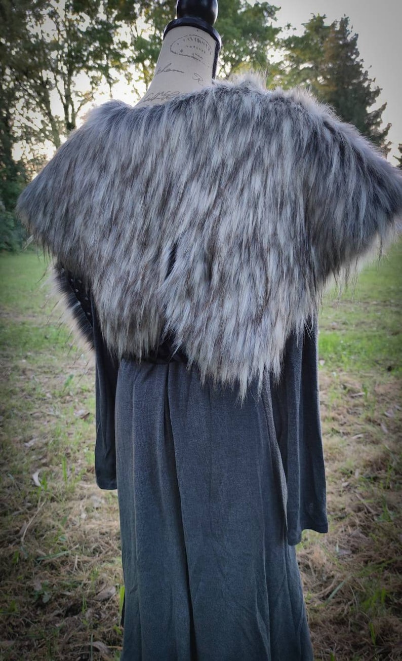 May include: A gray faux fur collar with a long gray dress underneath. The collar is made of soft, fluffy fur and has a slightly textured look. The dress is a simple, long-sleeved design.