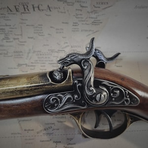 May include: A detailed, ornate, black and gold pistol with a wooden stock and a decorative, sculpted, dragon-like handle.