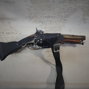 May include: A black leather holster with a strap for a flintlock pistol. The pistol is made of wood and metal and has a brass barrel.