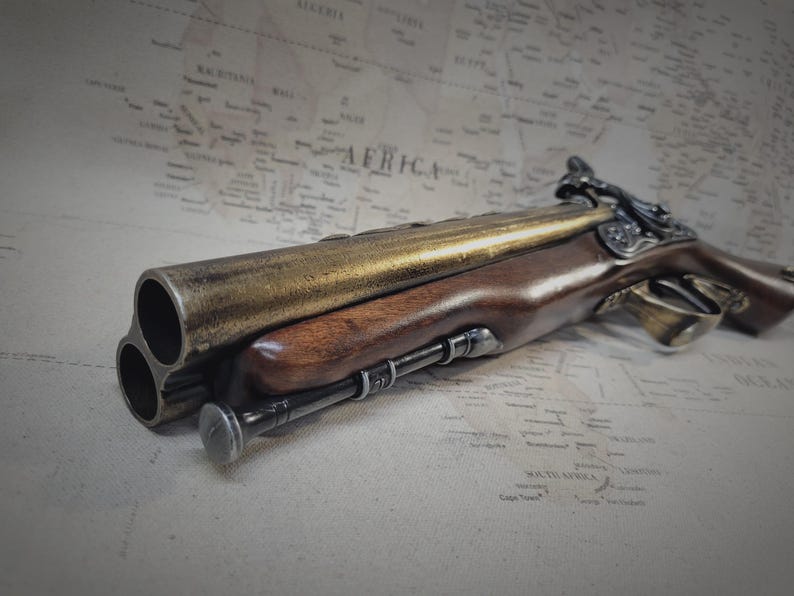 May include: A gold and brown antique-style triple-barreled pistol with a wooden handle and intricate metalwork.