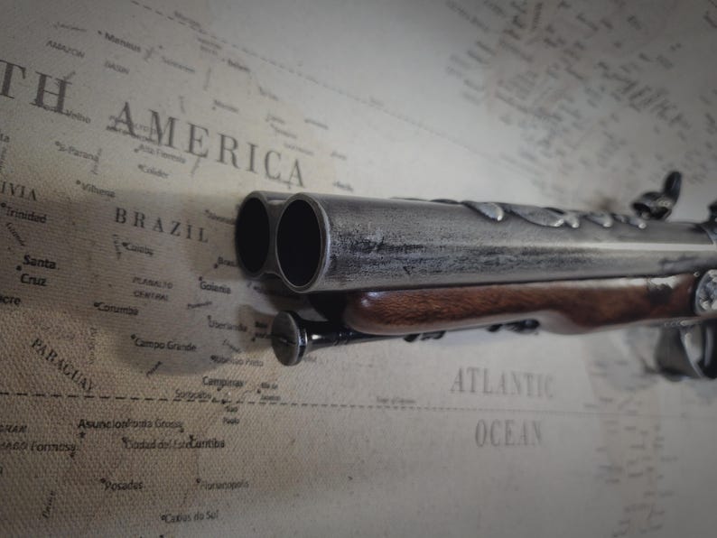 May include: A silver and brown double-barreled pistol with a wooden handle. The pistol is lying on a map of South America.