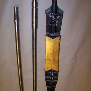 May include: Three metal spear points, one with a gold-painted tip, and two with silver-colored tips. The spear points are all attached to long, thin metal rods.