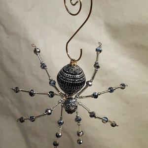 May include: A black and silver beaded spider Christmas ornament with a gold wire hanger.