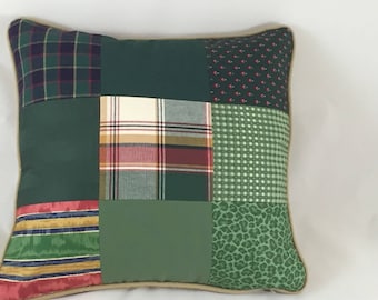 Puede incluir: Una almohada de patchwork verde, marrón y crema con ribete beige. La almohada está hecha de diferentes telas, incluyendo cuadros, flores y patrones geométricos.