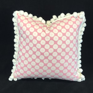 Pink and white young girl’s cushion with printed floral fabric, pompon braid and ribbon embellishment