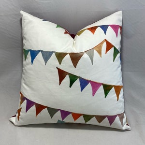 May include: A white throw pillow with a colorful watercolor design of bunting flags. The flags are in shades of red, orange, yellow, green, blue, purple, and pink.