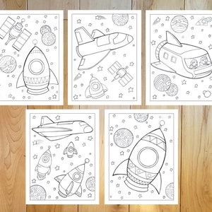 May include: Five black and white space-themed coloring pages. Each page features a different design, including rockets, spaceships, satellites, planets, and stars. The illustrations are outlined with thick black lines, perfect for coloring.