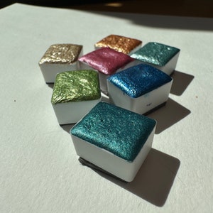 Different colors of sparkly watercolor paints.