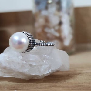 Może przedstawiać: Srebrny pierścionek z białą perłą osadzoną w fakturowanym obrączce.