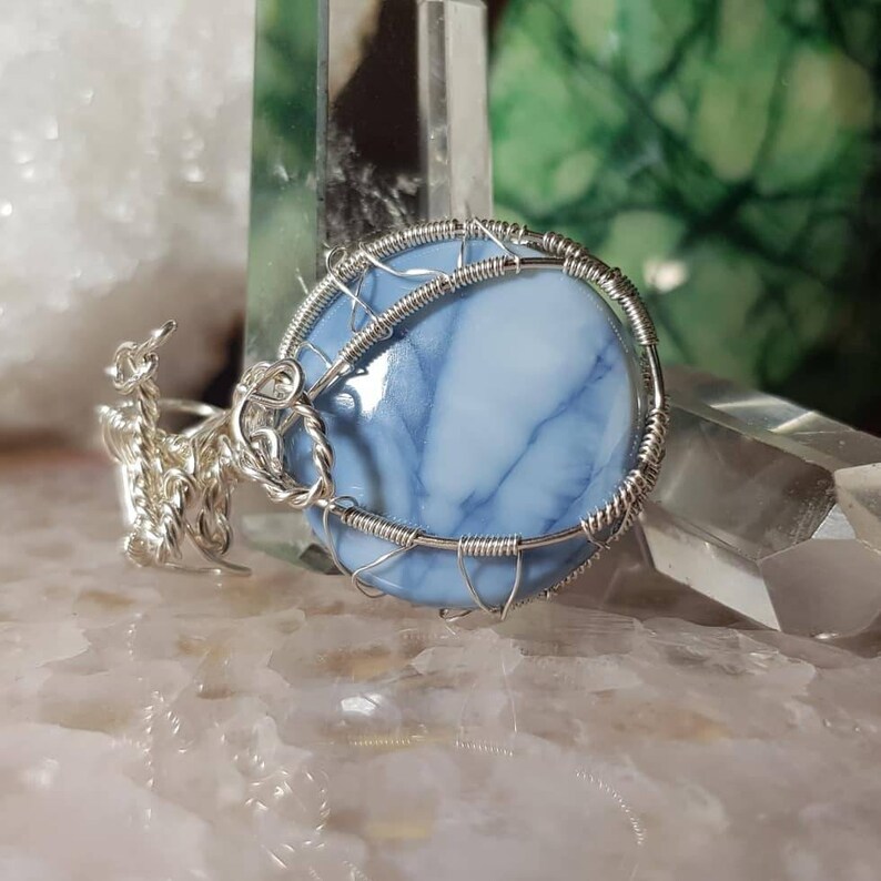 May include: A blue and white agate gemstone pendant wrapped in silver wire.