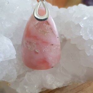 May include: A pink opal pendant with a silver bail. The opal has a swirling pattern of pink and white.