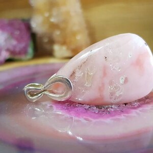 May include: A pink and white teardrop-shaped gemstone pendant with a silver bail.
