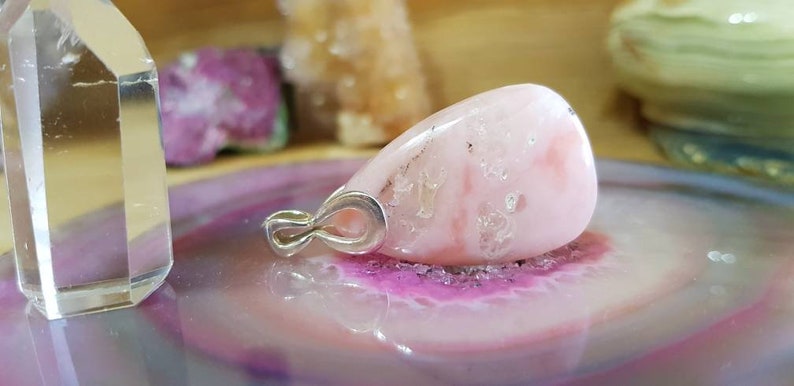 May include: A pink and white teardrop-shaped gemstone pendant with a silver bail.