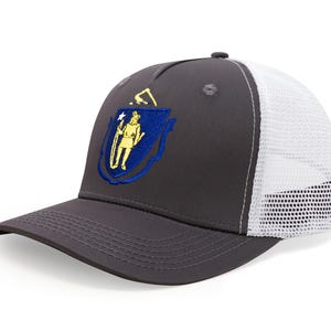 May include: A gray trucker hat with a white mesh back and a curved brim. The front of the hat features an embroidered emblem with a blue shield and a yellow figure. The hat has a snap closure.