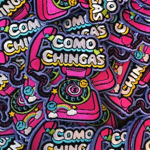 May include: Embroidered patches with a retro telephone design in shades of pink, purple, and blue. The patches feature the text "COMO CHINGAS" in a colorful, playful font, with accents like rainbows and stars.