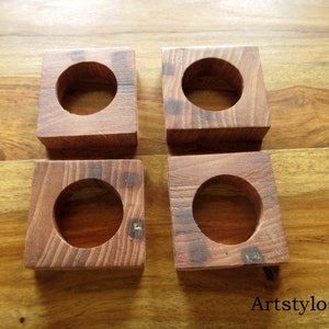 Puede incluir: Cuatro posavasos cuadrados de madera con un hueco circular en el centro. Los posavasos son de madera de color marr&oacute;n rojizo y est&aacute;n colocados sobre una superficie de madera. El texto "Artstylosbois" es visible en la esquina inferior derecha.
