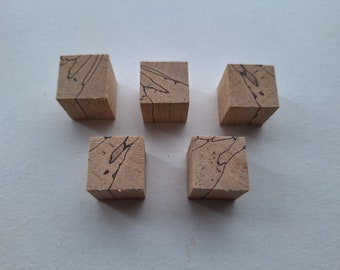 May include: Five small, square wooden blocks with a light brown color and dark, vein-like patterns. The blocks are evenly spaced and appear to be made of natural wood, possibly for crafting or decorative purposes.