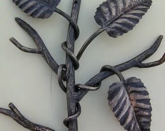 May include: A black metal wall decor in the shape of a stylized tree with three leaves. The leaves have a textured, striped pattern.