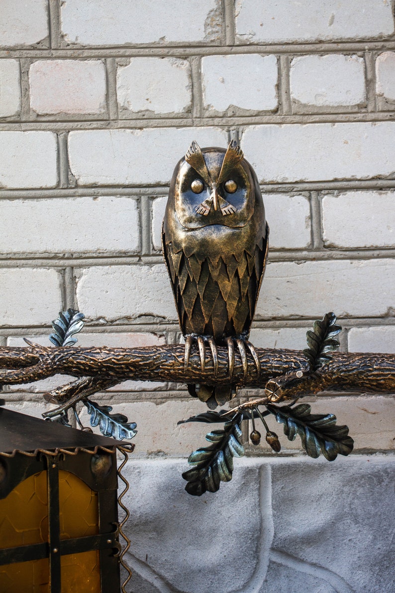 Wrought sconce in the form of an oak branch on which an owl sits with a lantern