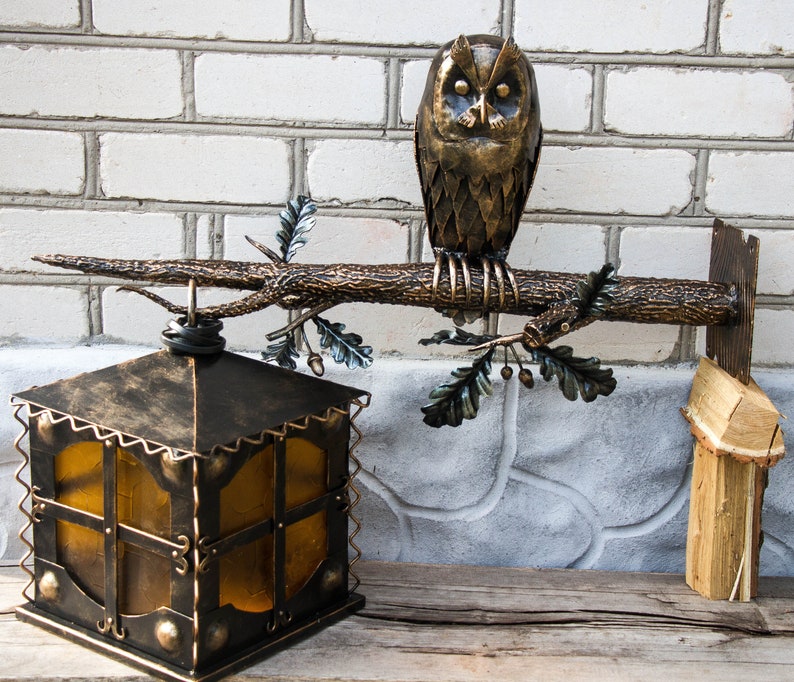 Wrought sconce in the form of an oak branch on which an owl sits with a lantern