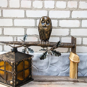 Wrought sconce in the form of an oak branch on which an owl sits with a lantern