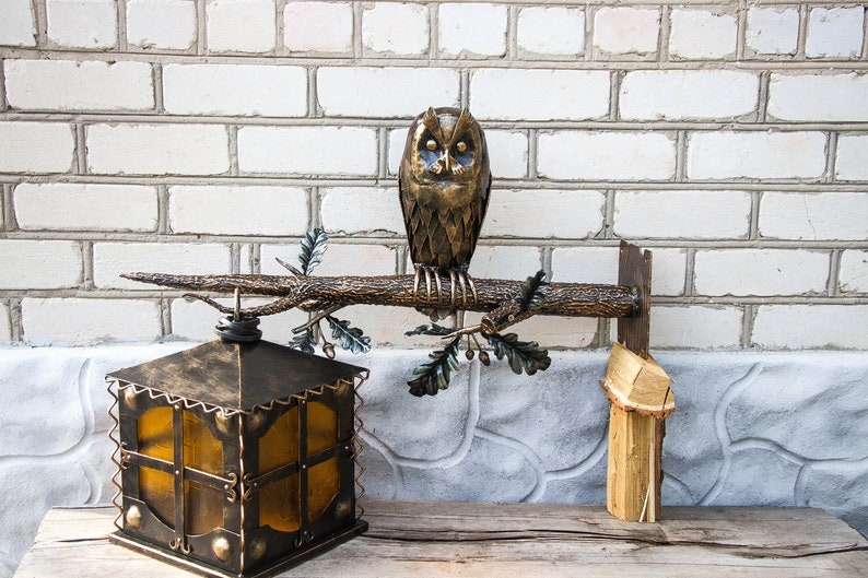 Wrought sconce in the form of an oak branch on which an owl sits with a lantern