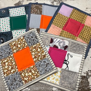 May include: Five handmade patchwork fabric coasters with different patterns and colors. The coasters are made of various fabrics, including floral, paisley, plaid, and gingham. Each coaster has a square shape and a contrasting fabric border.
