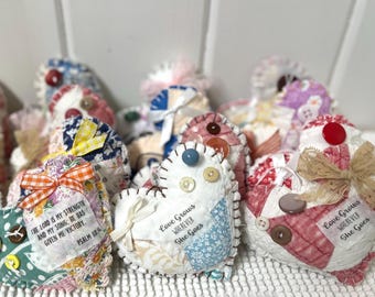 Puede incluir: Una colección de adornos de corazón de tela hechos a mano con varios patrones y colores. Algunos corazones presentan citas inspiradoras, que incluyen "El Señor es mi fortaleza y mi canción: Él me ha dado la victoria." y "El amor crece dondequiera que ella vaya."