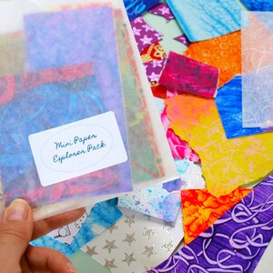 May include: A cellophane bag containing a Mini Paper Explorer Pack with colourful paper scraps. The label on the bag reads "Mini Paper Explorer Pack". There are additional colourful paper pieces in various shapes and sizes scattered around the bag.
