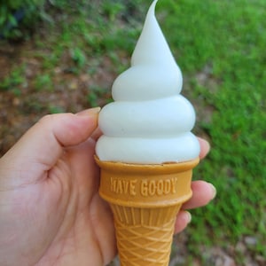 May include: A white soft serve ice cream cone with the words "Have Goody" printed on the cone.