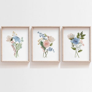 May include: Three framed watercolor paintings of floral bouquets. Each painting features a different arrangement of blue, pink, and white flowers with green leaves.