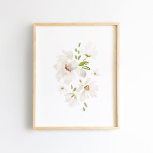 May include: A framed watercolor print featuring a cluster of white flowers with delicate petals and green leaves. The artwork is set against a white background, and the frame is made of light-colored wood.